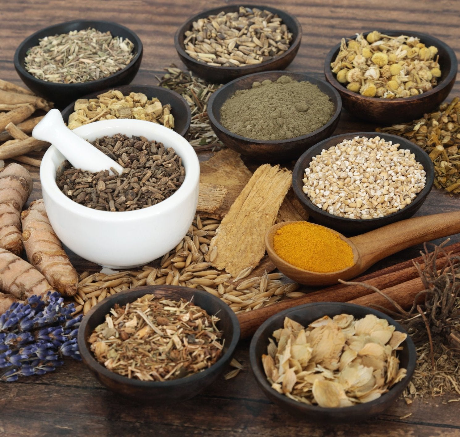 An herbal display of several different adaptogens, in their raw natural form. Placed in differing bowls, all laid on top of wooden table.