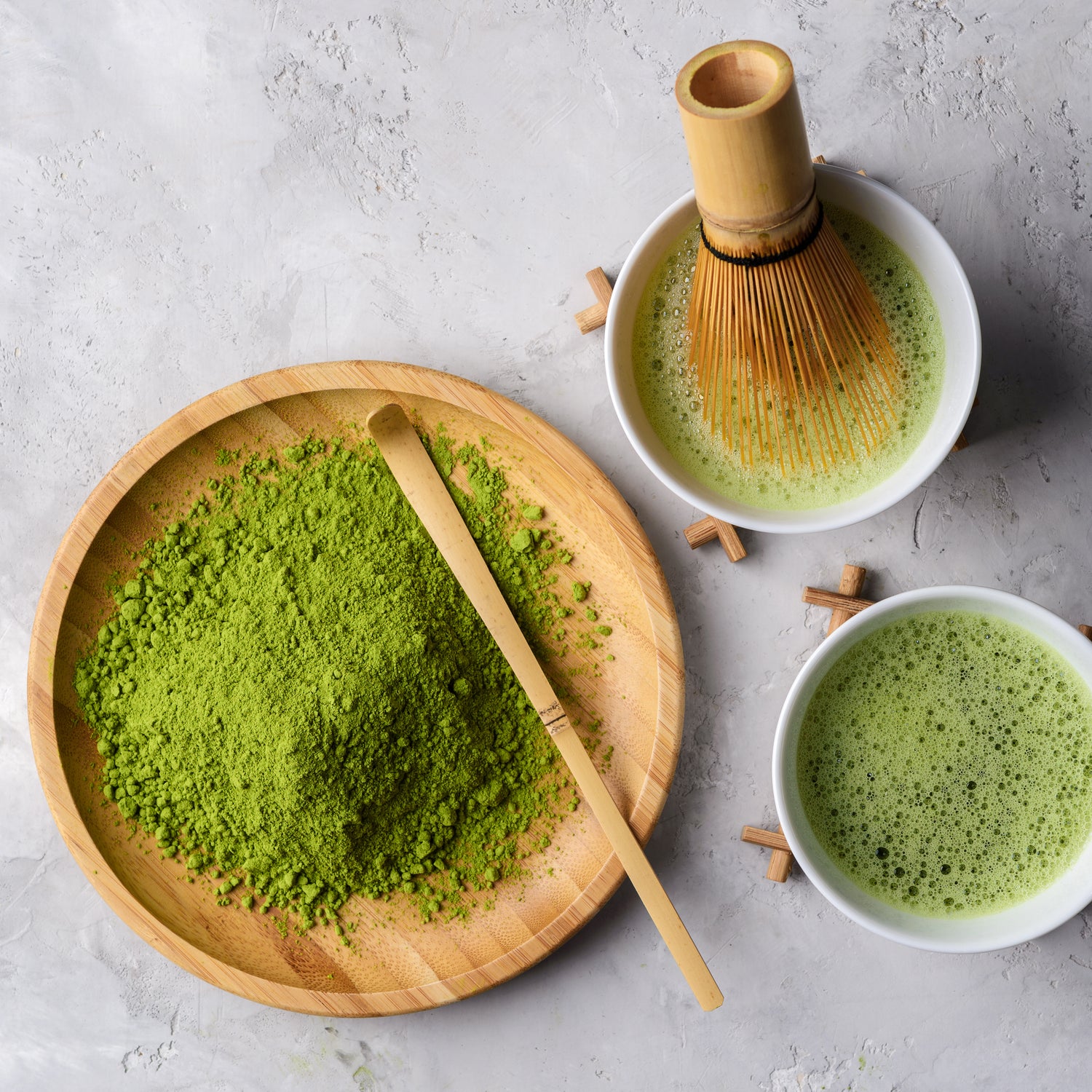 Stone Background. Matcha powder, with matcha spoon, matcha whisk, and foamy, bubbly prepared matcha concentrate.