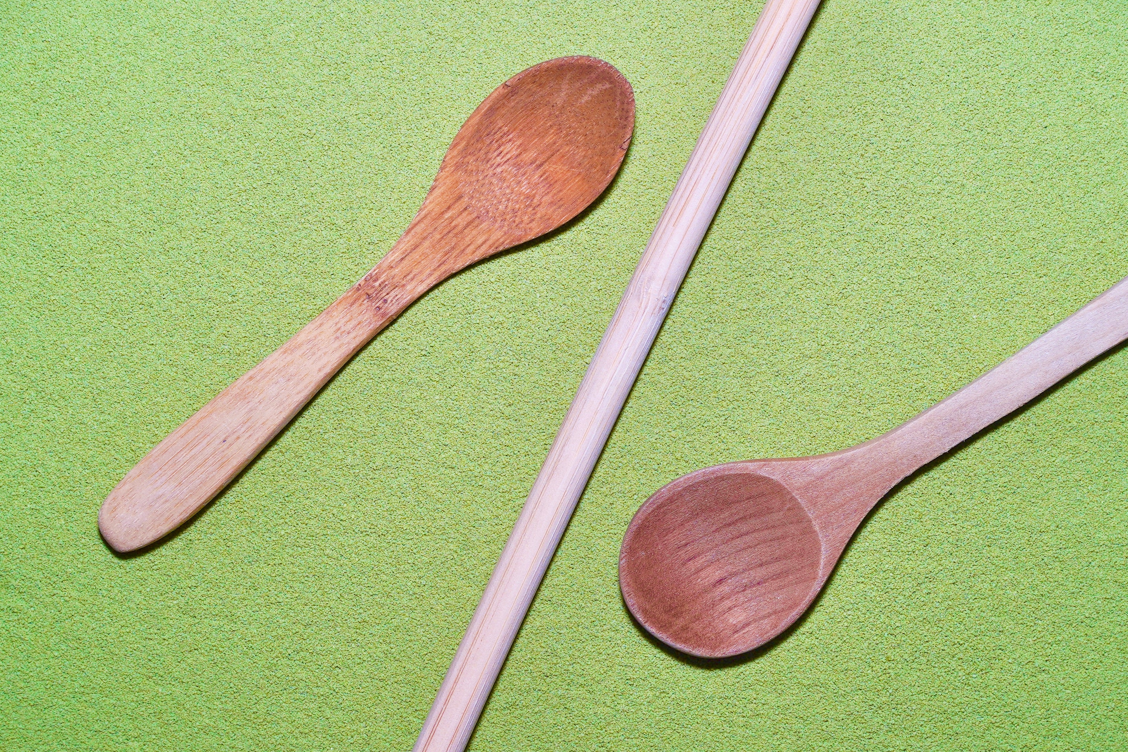 Sage Matcha Latte powder spread across. Wooden Spoons and bamboo straw laid on top of matcha.